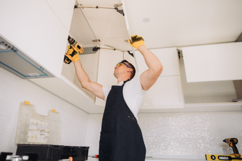 Technician using a cordless drill on a kitchen installation