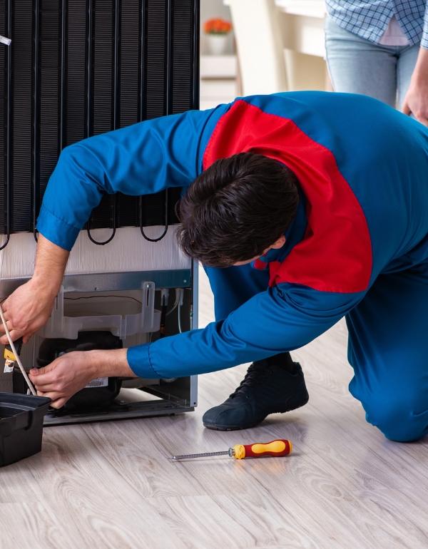 Technician repairing the back of a refrigerator